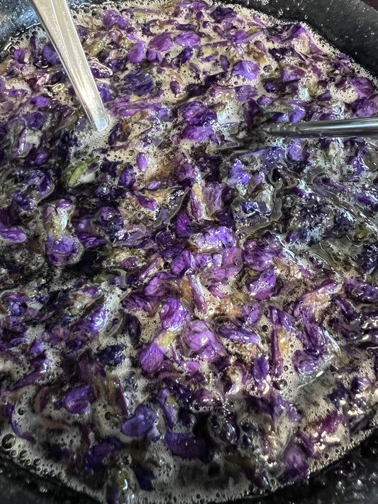 Wild Violets simmer in honey in a pot on the stove