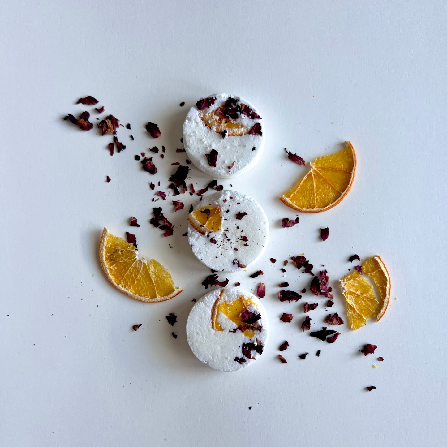 Shower steamers with orange slices and dried herbs on a light gray background