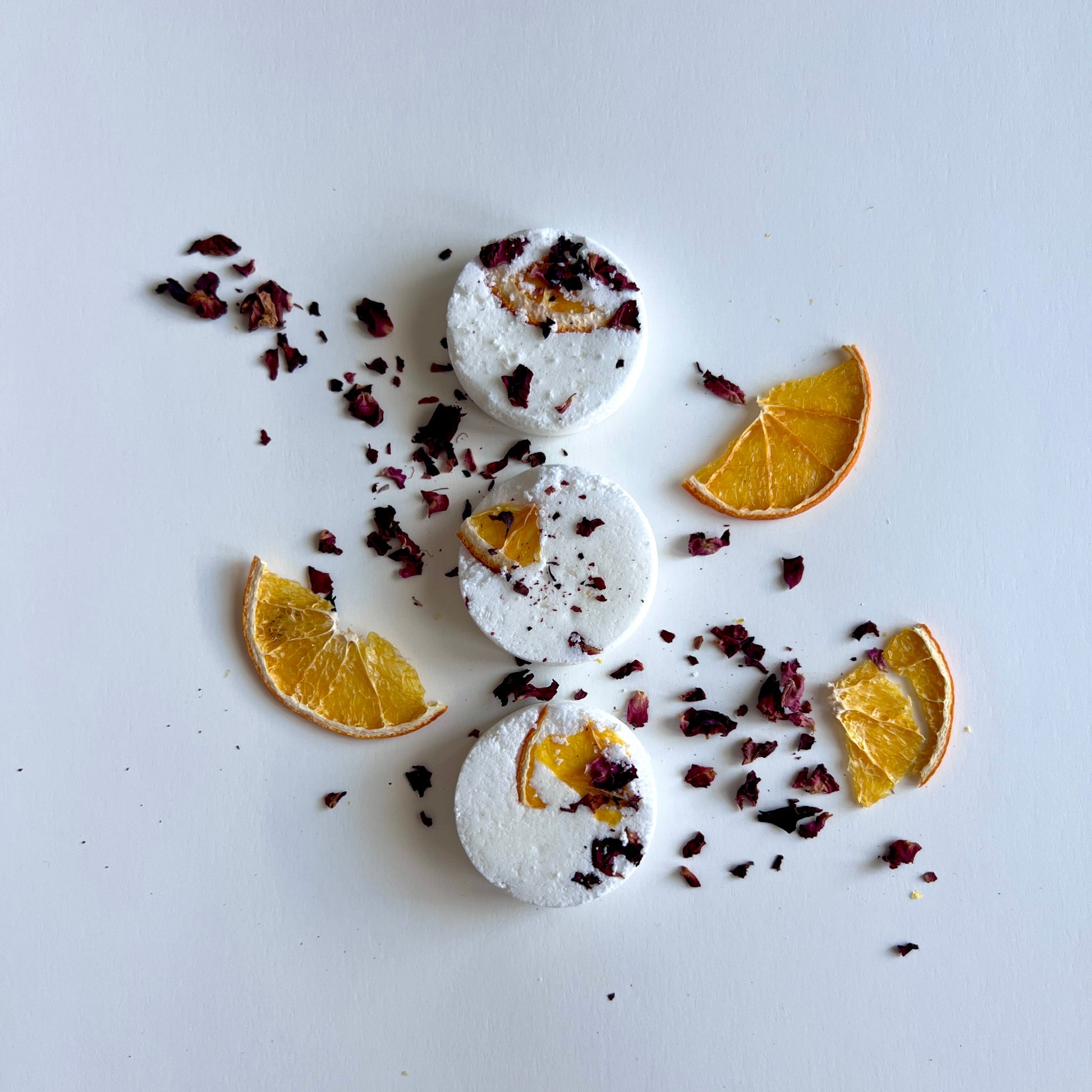 Shower steamers with orange slices and dried herbs on a light gray background