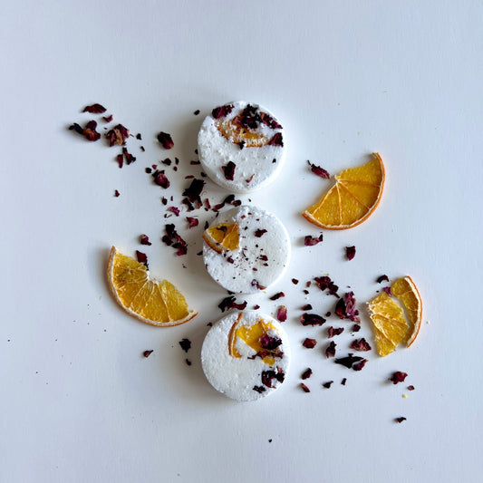 Shower steamers with orange slices and dried herbs on a light gray background